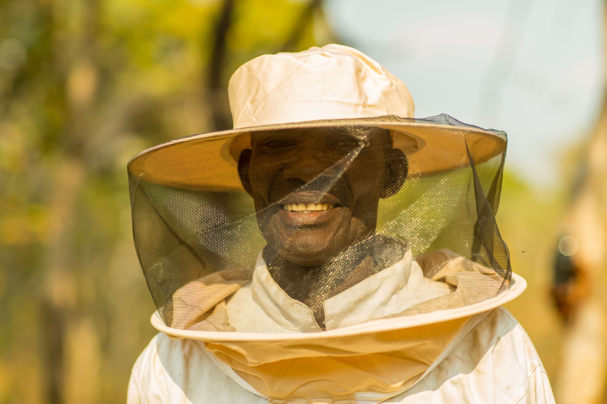 A smiling beekeeper in a protective veil