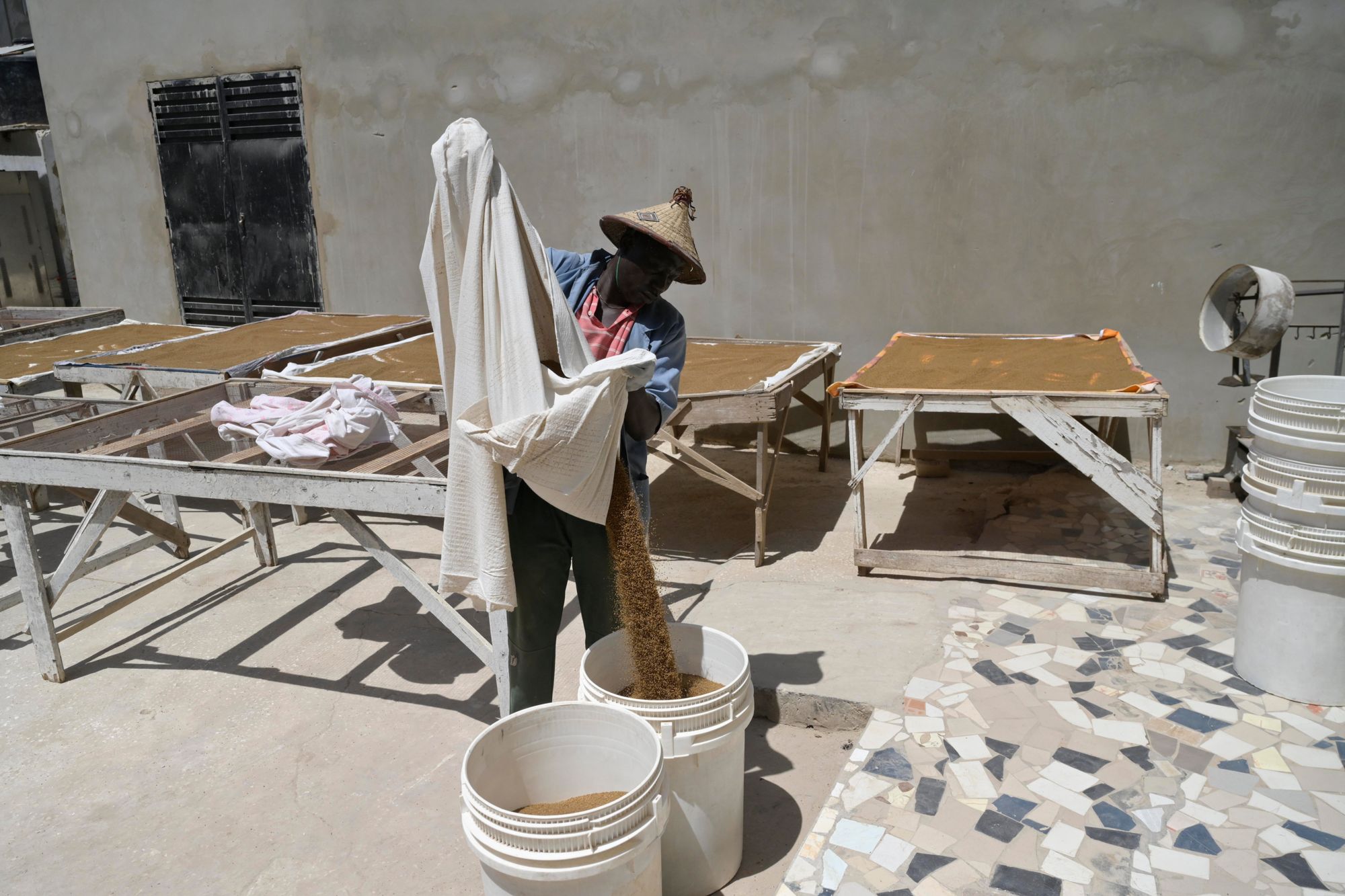 A worker pours dried grain into a bucket at Kumba in Senegal